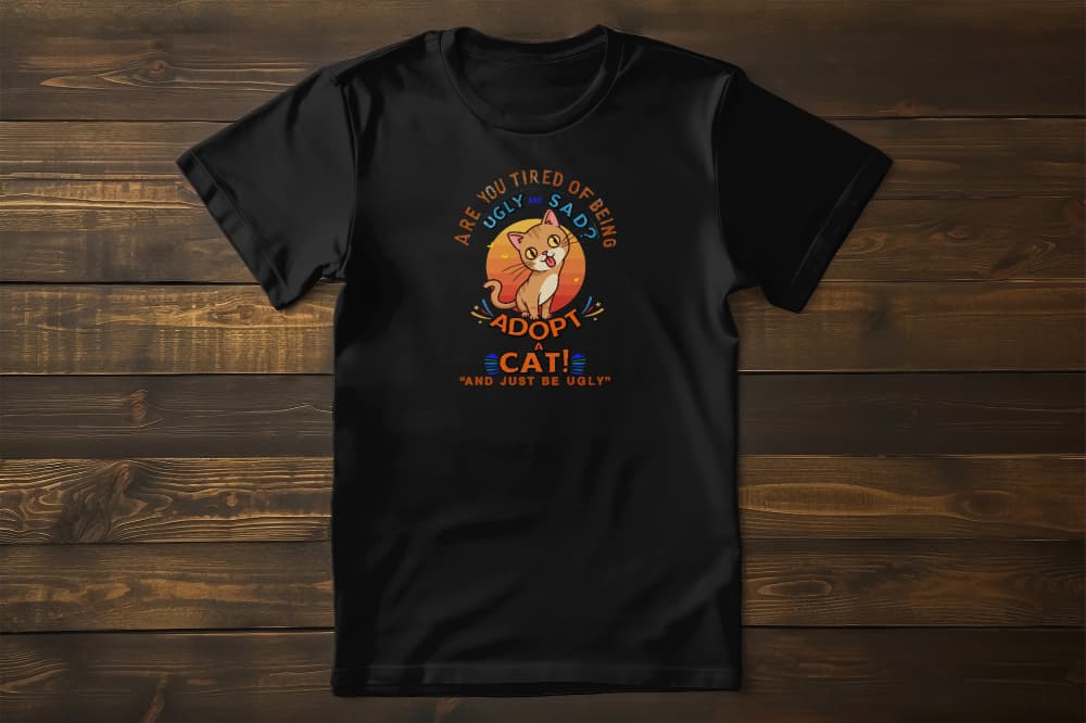 Flat lay of Funny Sarcastic Cat t-shirt featuring tongue-out cat under the sun with sarcastic quote Adopt a Cat