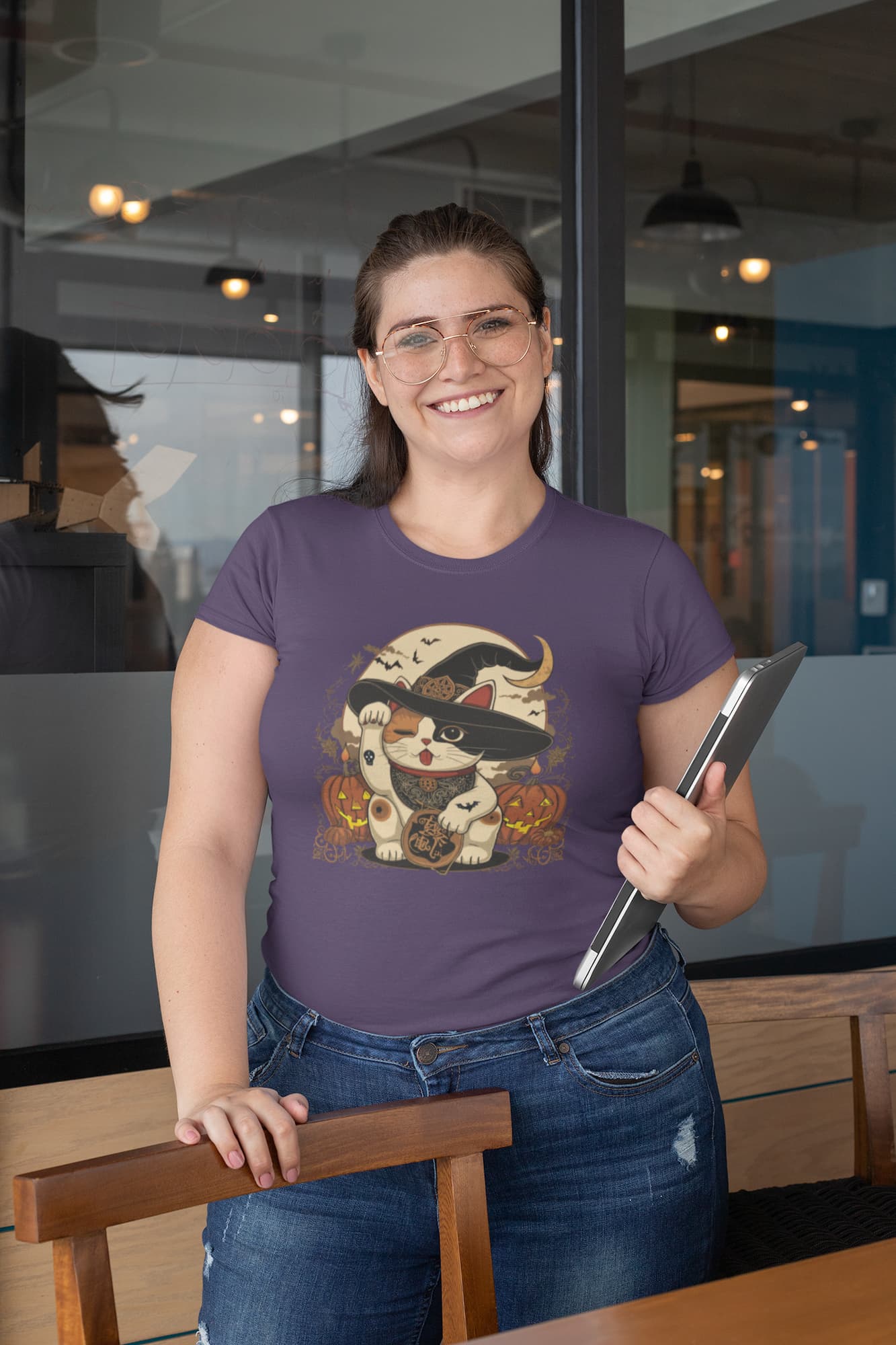 Model wearing classic women’s Witchy Neko Halloween t-shirt with artistic lucky cat design in orange, gold, and cream tones