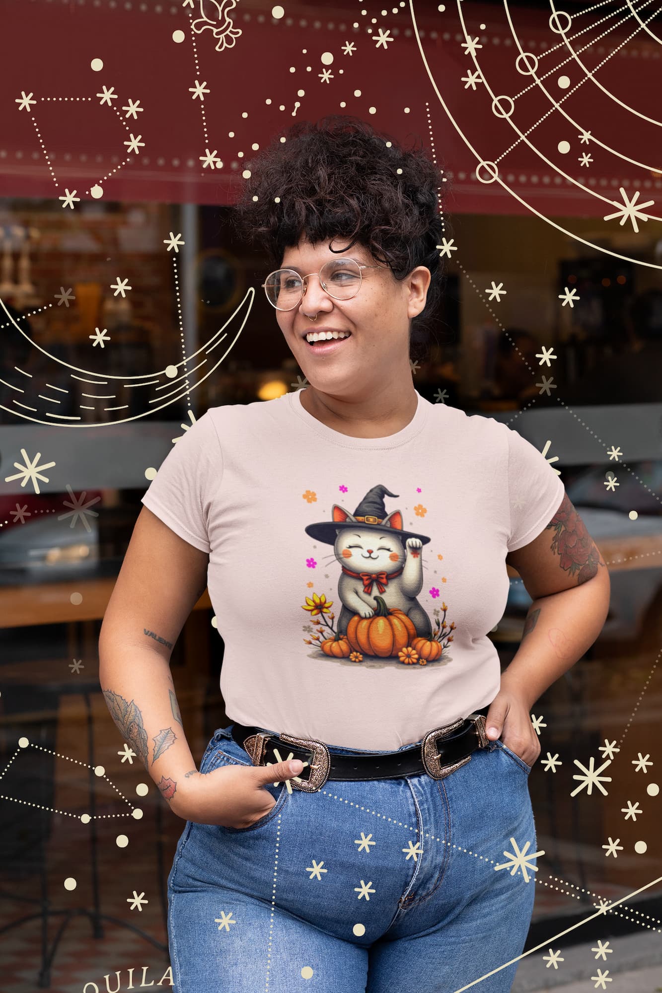 Model wearing Witch Luck Halloween cat t-shirt with lucky Maneki-neko cat in witch hat surrounded by colorful flowers, feminine and mystical design