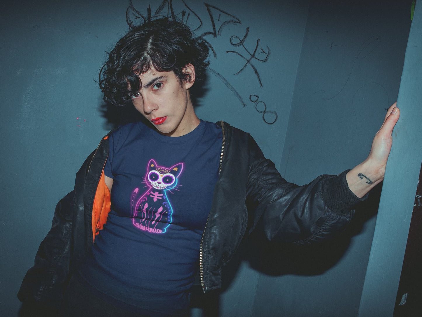 Woman styling Muertos Neon T-Shirt – colorful Día de los Muertos cat design with retro neon aesthetic.