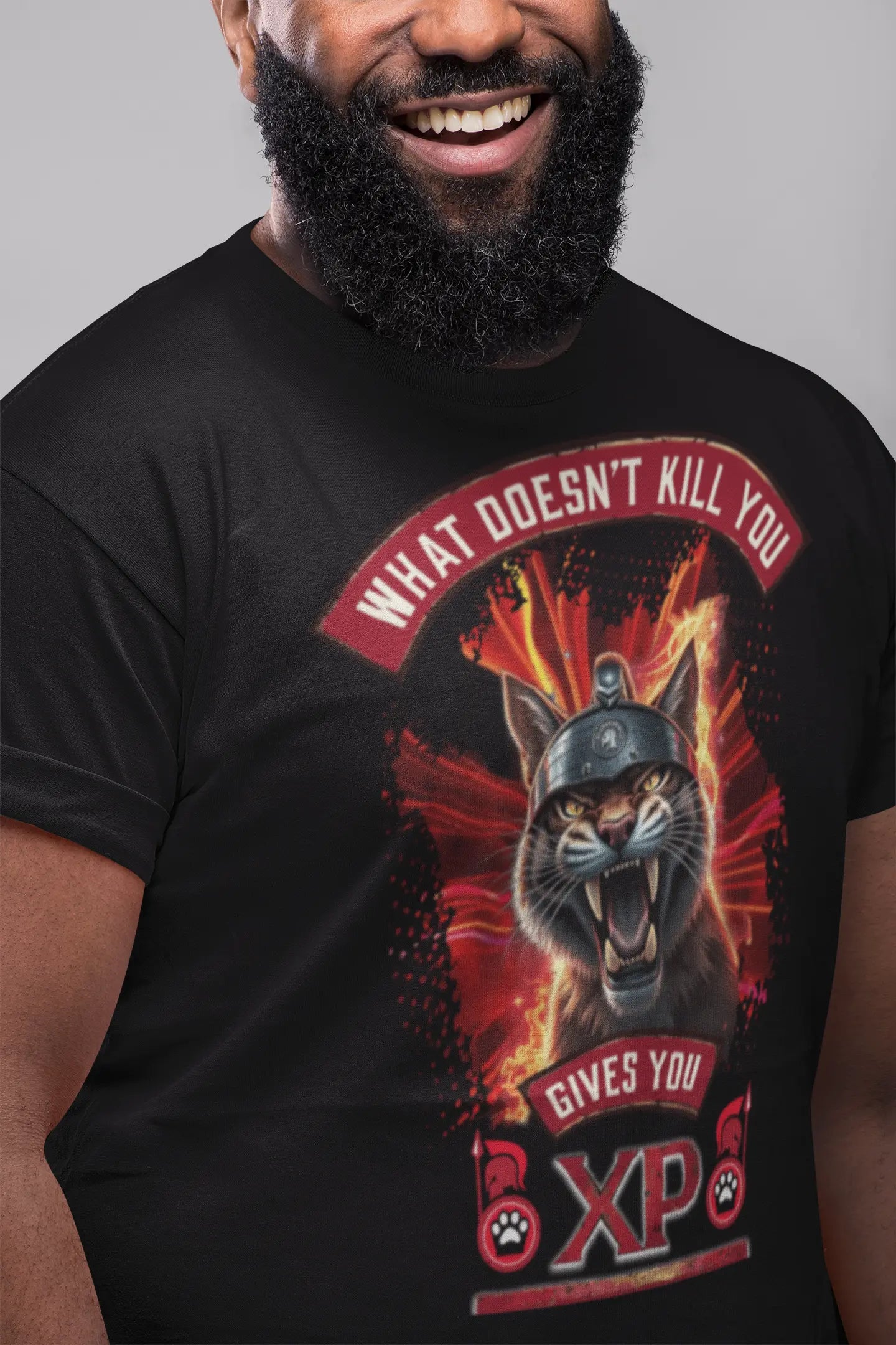 Smiling young person wearing the black Felinamia t-shirt featuring the Spartan cat print and the phrase "What Doesn't Kill You Gives You XP", showing the garment's fit in a casual setting.