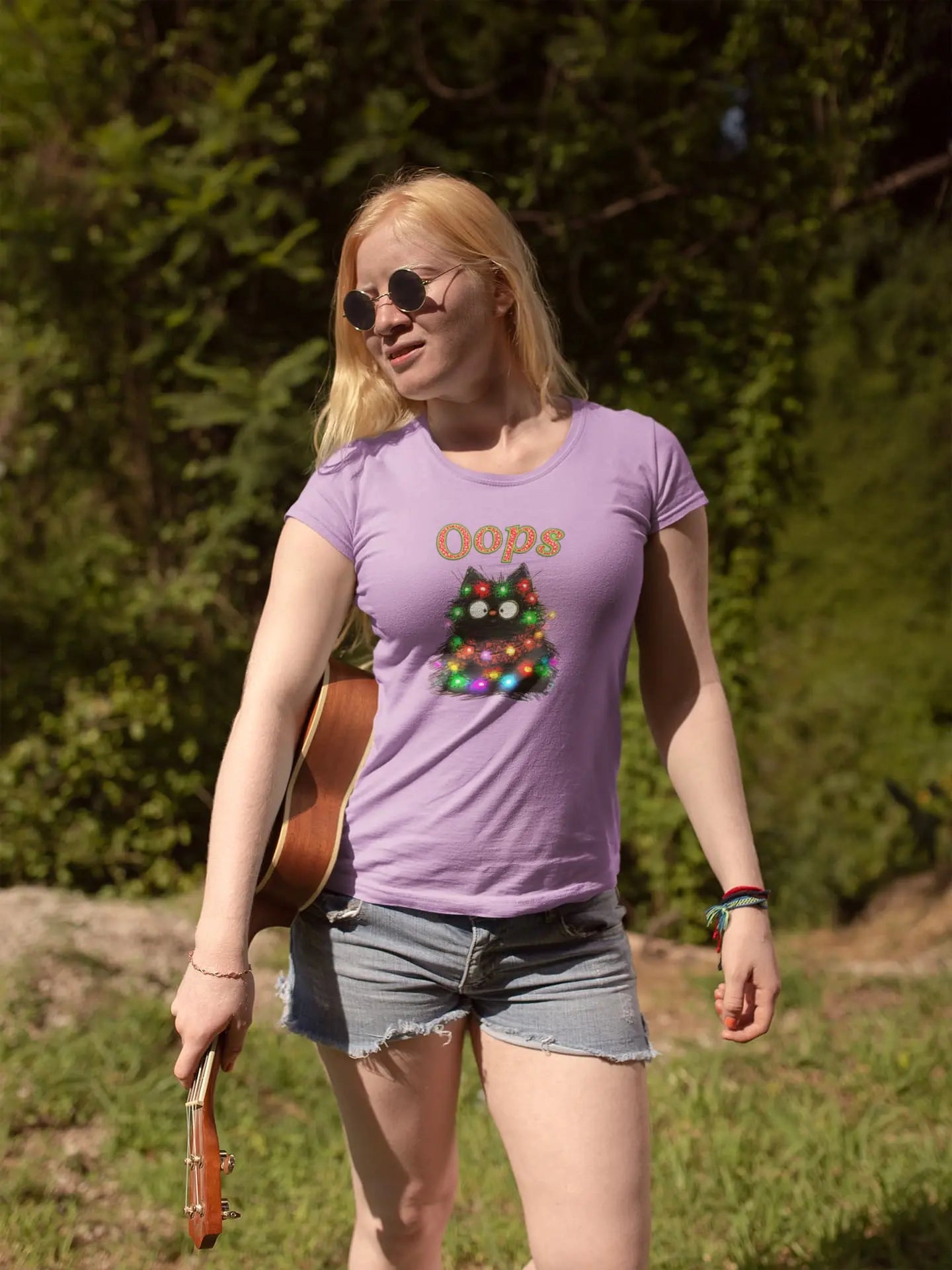 Person wearing Santa Claws Oops Cat T-Shirt while decorating Christmas tree – funny festive shirt for cat owners and holiday lovers.