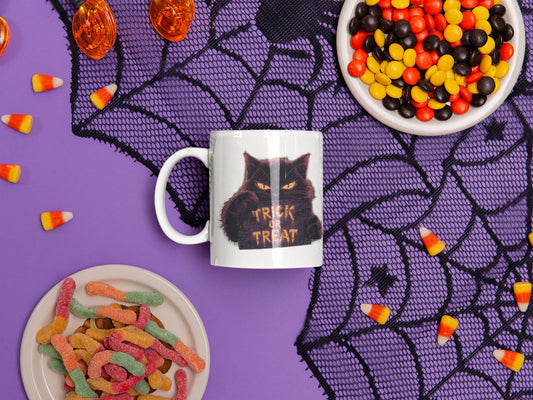 11oz ceramic mug Cursed Candy – mysterious cat with glowing Trick or Treat sign, part of Felinamia’s Meowlloween collection.
