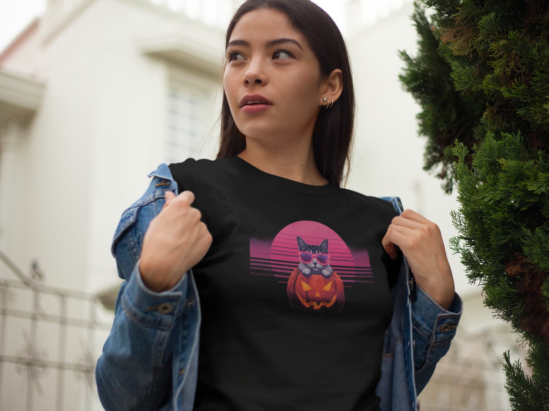 Model wearing Neon Pumpkin Cat T-Shirt – unisex premium tee featuring neon cat inside jack-o’-lantern with synthwave sunset.